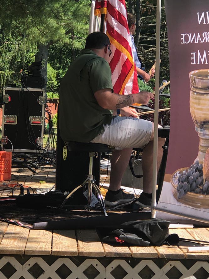 Man playing drums with American flag alongside him