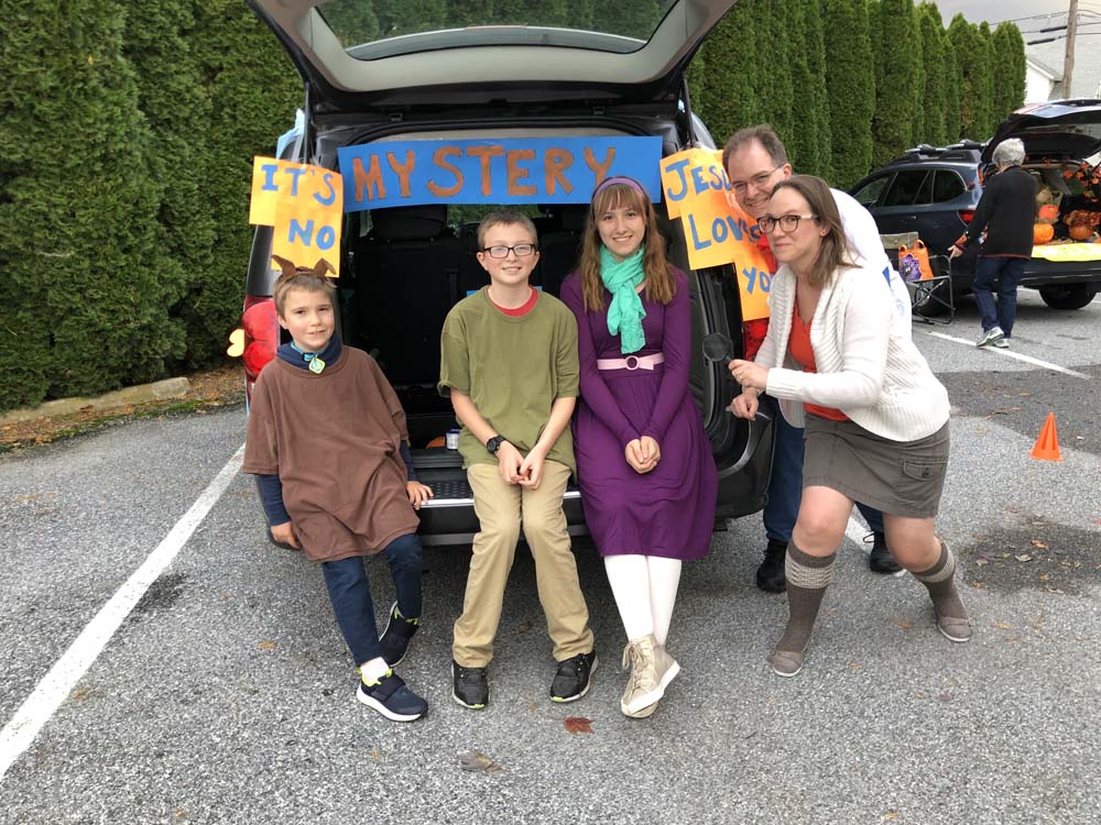 Kids in costumes next to adults infront of car